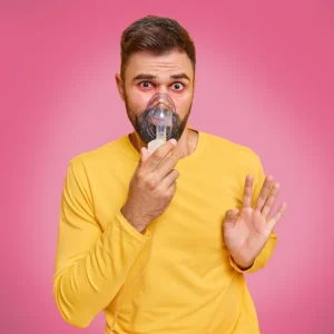 Ein junger Mann mit dunklen Haaren und Bart nutzt eine Inhalationsmaske