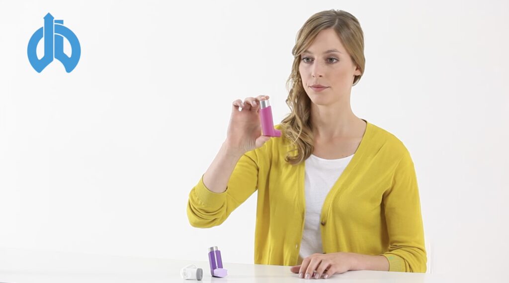Eine Frau hält ein Dosieraerosol in der Hand.